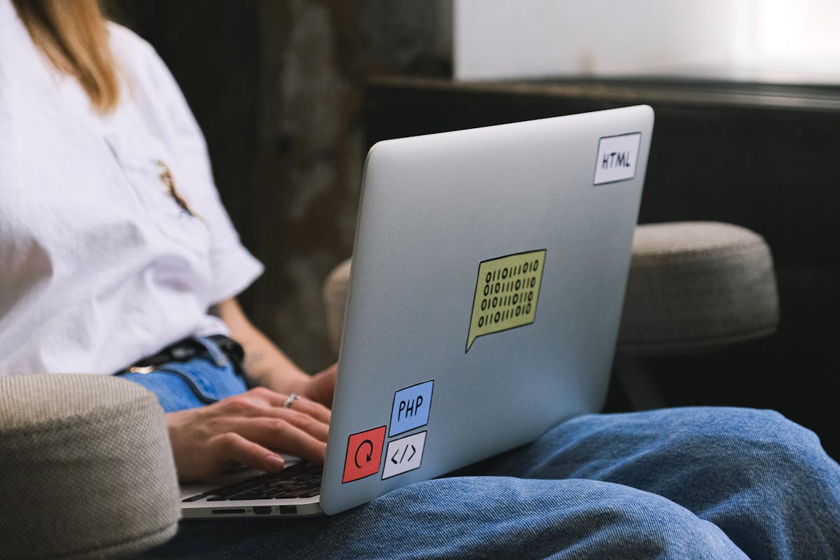 Person working remotely on a laptop with coding stickers, representing freelance tech work