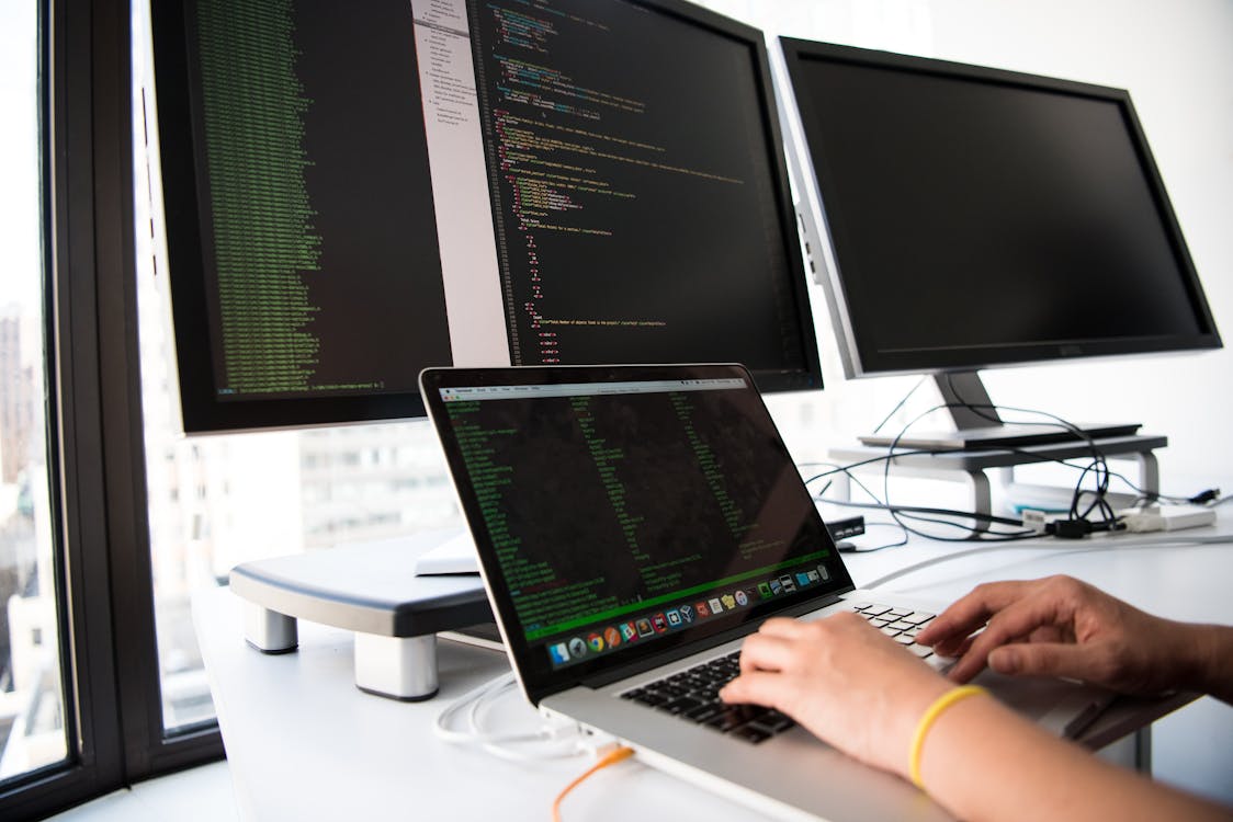 Developer working on evaluation code with multiple monitors showing data analysis