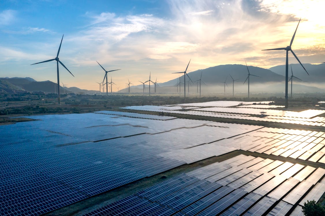 Wind turbines and solar panels at sunset in a renewable energy landscape